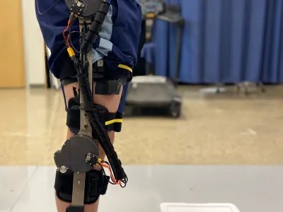 The M-BLUE knee module worn over clothing, showing the actuator and its mounting brace.