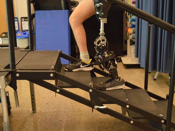 A powered knee-ankle prosthesis descending a stair rig, one of the activities this controller supports.